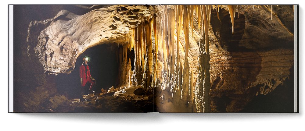 Sample double page of the 'New Zealand Karst' book showing a caver next to an array of stalagmites and stalactites