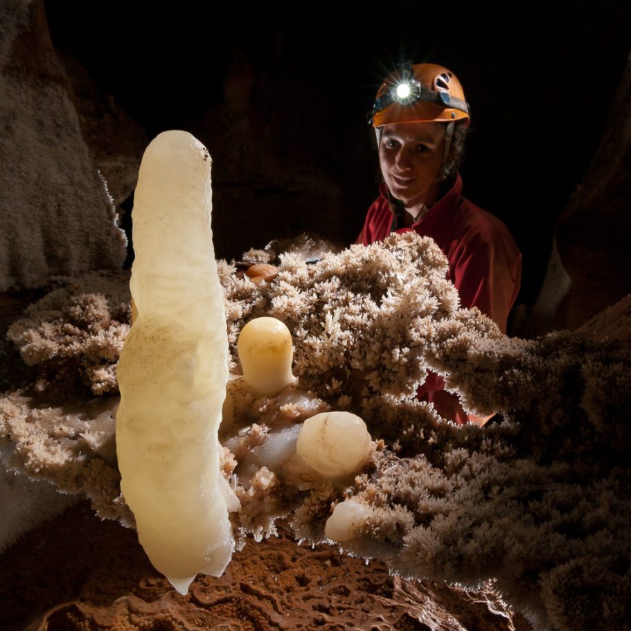 Caver looking at pristine white calcite stalagmites and floor crystals