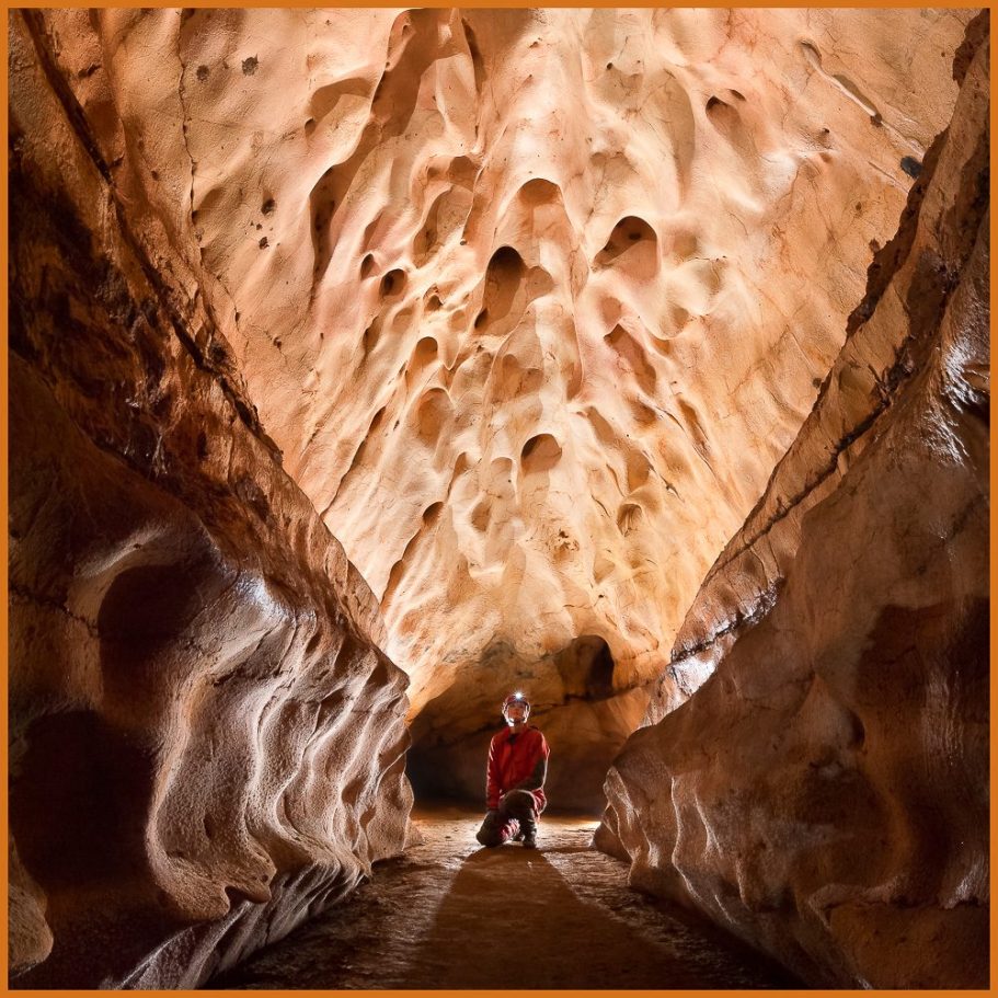 A caver in a cave passages with scallops on the walls; title photo for "Passages and Pits" portfolio