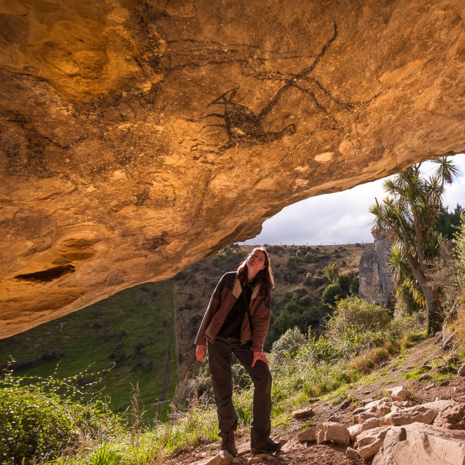 Person looking at Maori rock art on the ceiling of a limestone rock shelter in New Zealand
