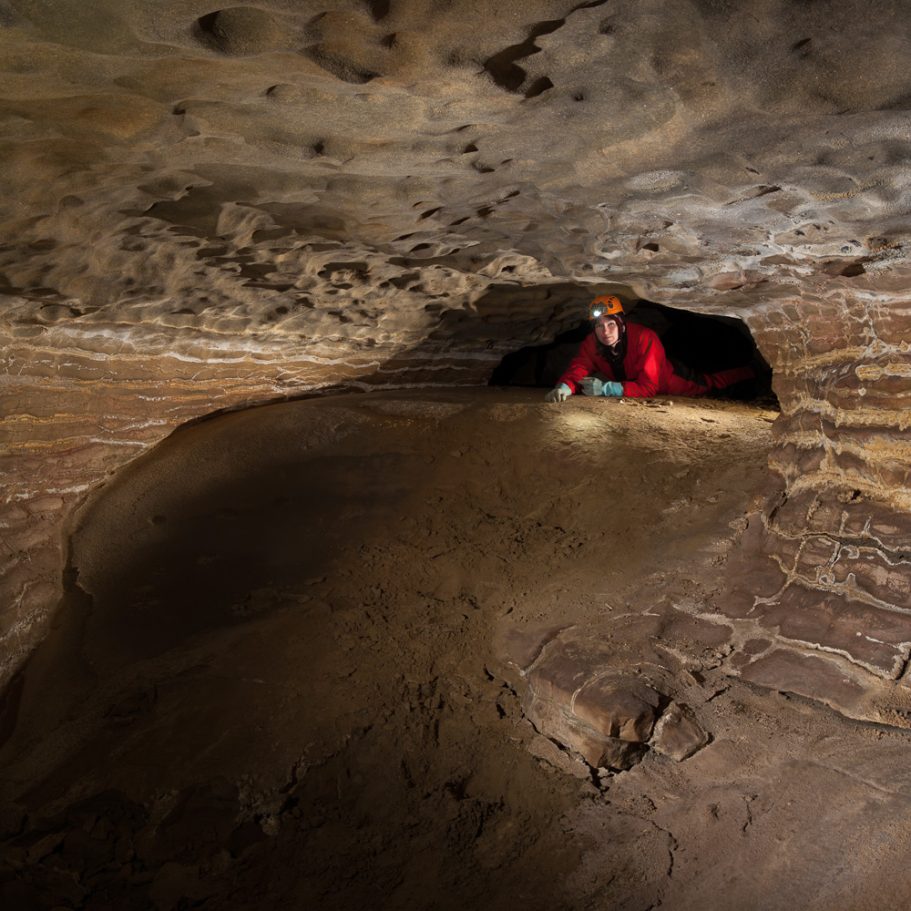 Caver crawling in a low passage