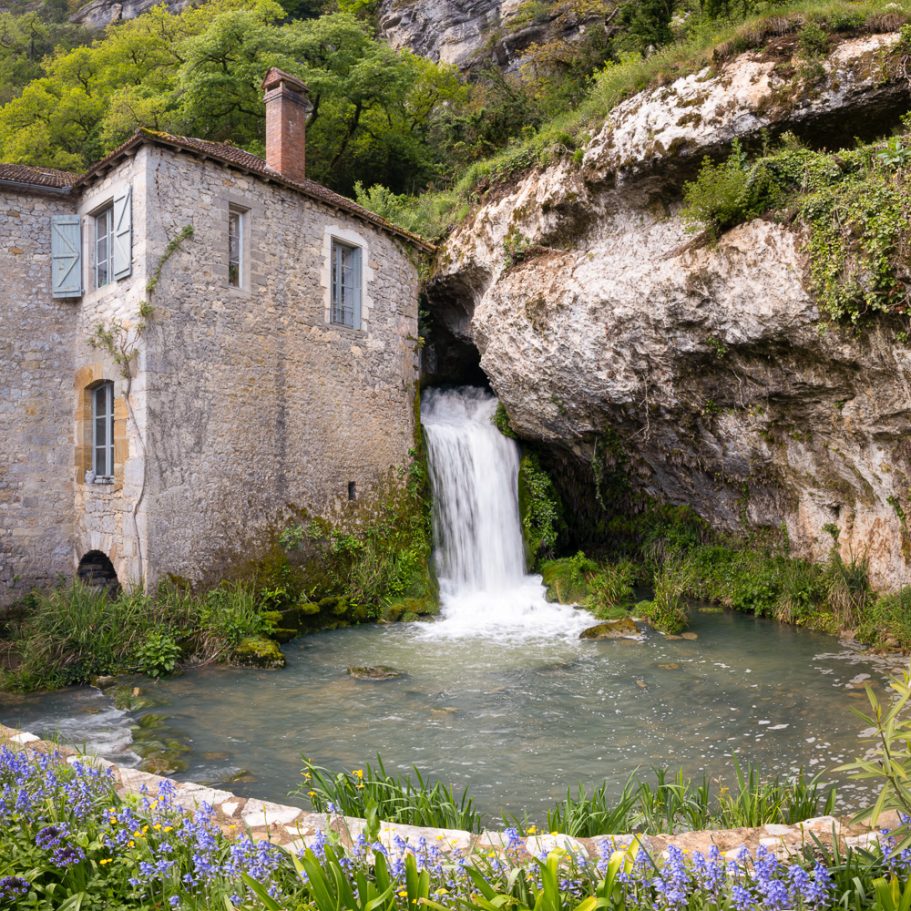 Karst spring and waterfall with stony building next to it