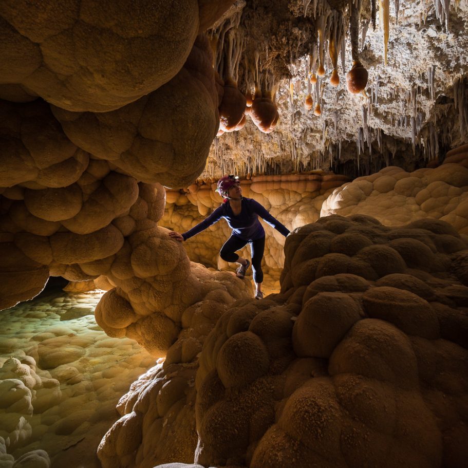 Caver climbing across cloud shaped calcite pool lining at 'Lake Castrovalva' in Lechuguilla Cave