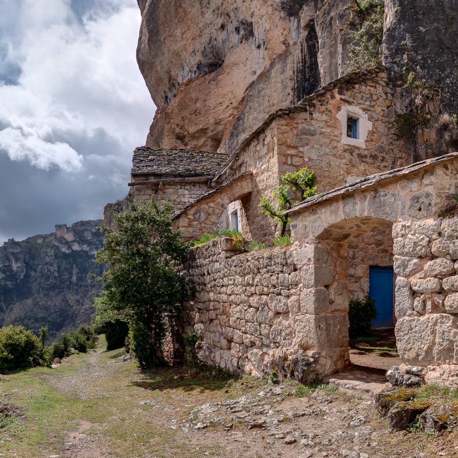 Ancient troglodytic buildings below an overhang in a limestone cliff