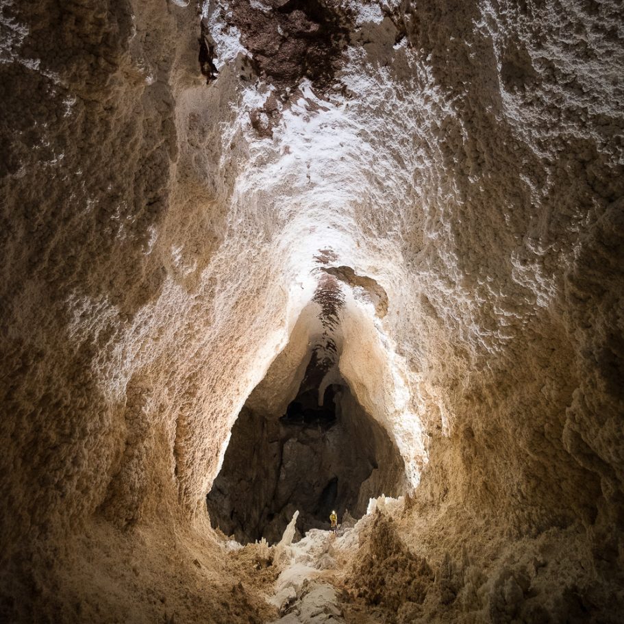 large borehole-type cave passage with caver for scale