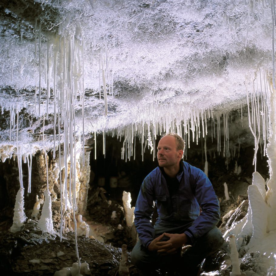 Caver in a passage with pure-white soda straw stalactites and lots of helictites