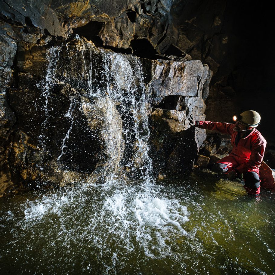 Cave waterfall with caver looking at it