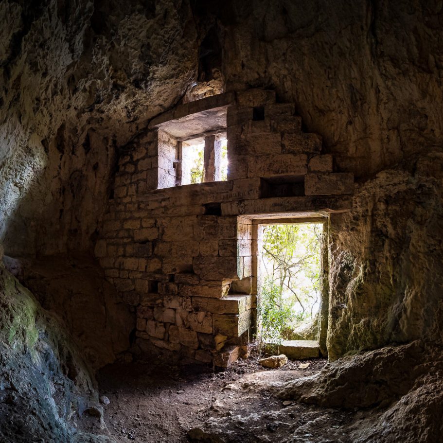 Ancient wall with door and window in a cave entrance seen from inside