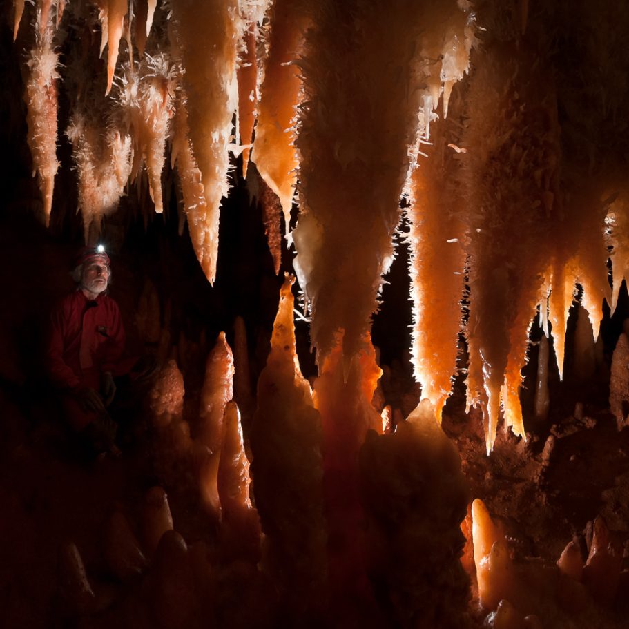 Array of stalactites and stalagmites covered in delicate calcite helictites; caver for scale