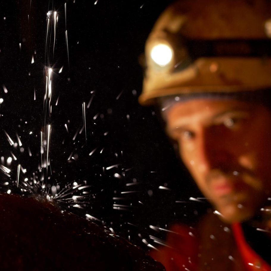 Caver looking at splashing water on a flowstone cascade
