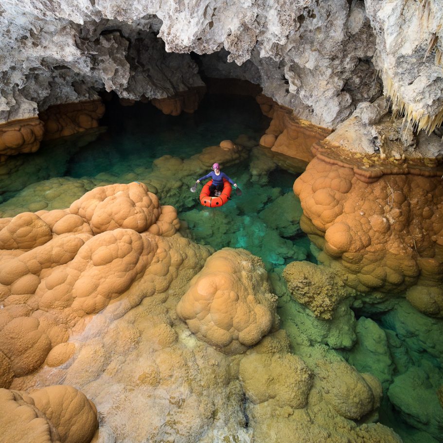 Caver traversing a deep cave pool called 'Lake Castrovalva' in Lechuguilla Cave