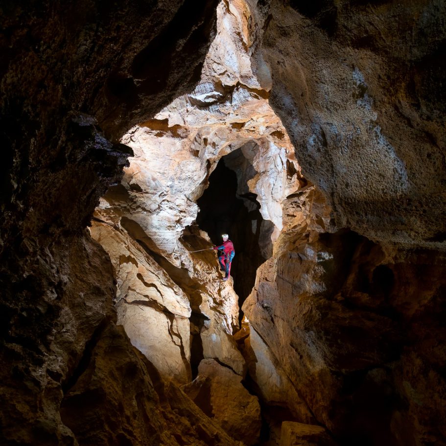 Caver in a passage with rope traverse