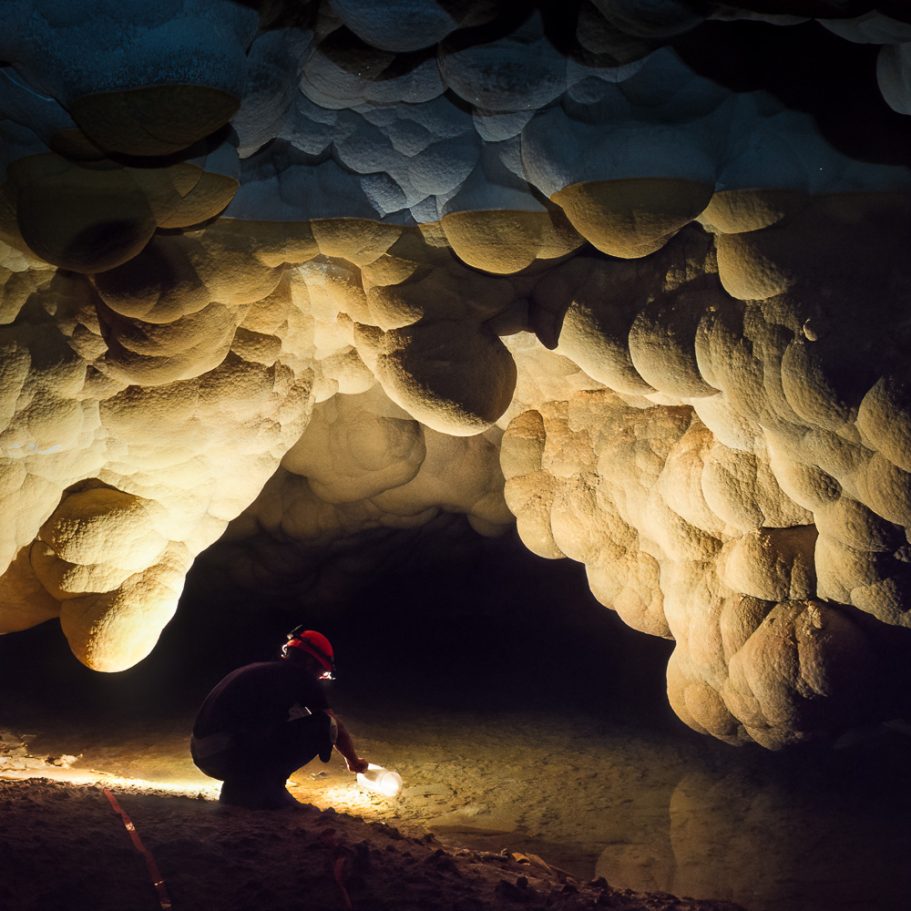 Cave explorer fetching drinking water with a pitcher at 'Lake Louise' in Lechuguilla Cave 