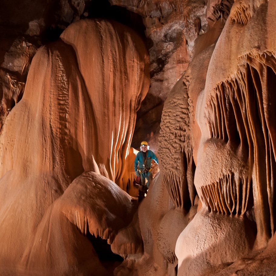 Caver with calcite speleothems