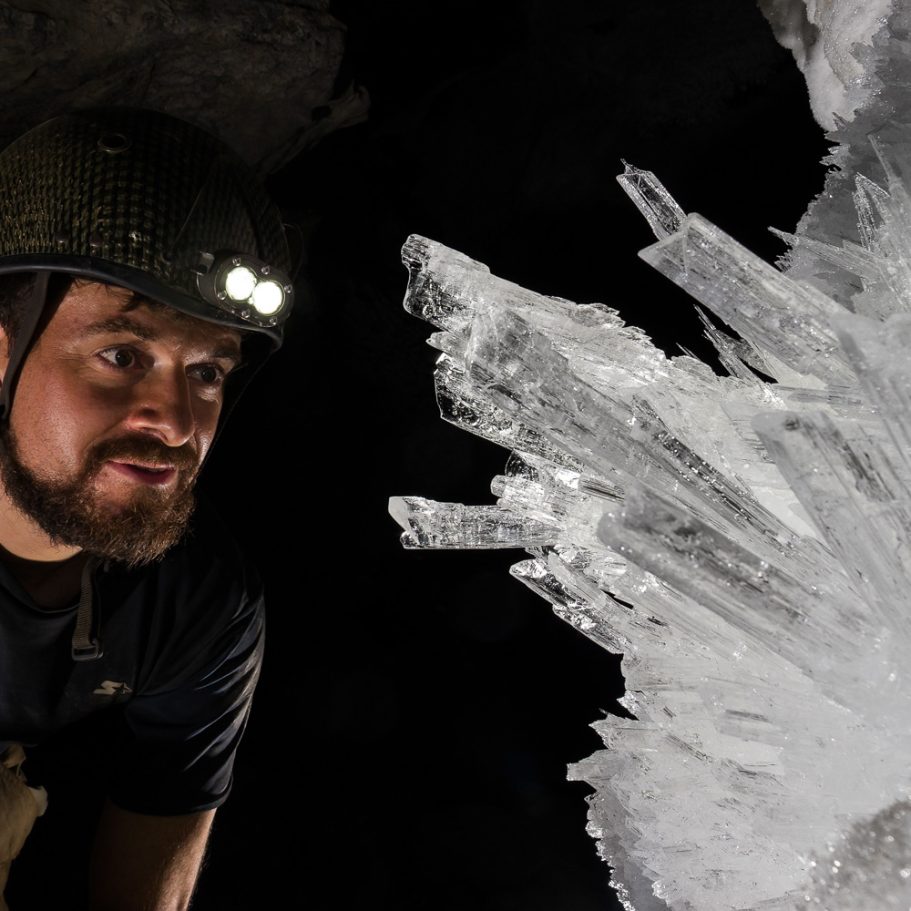 Caver looking at crystal clear, bladed selenite crystals in Lechuguilla Cave