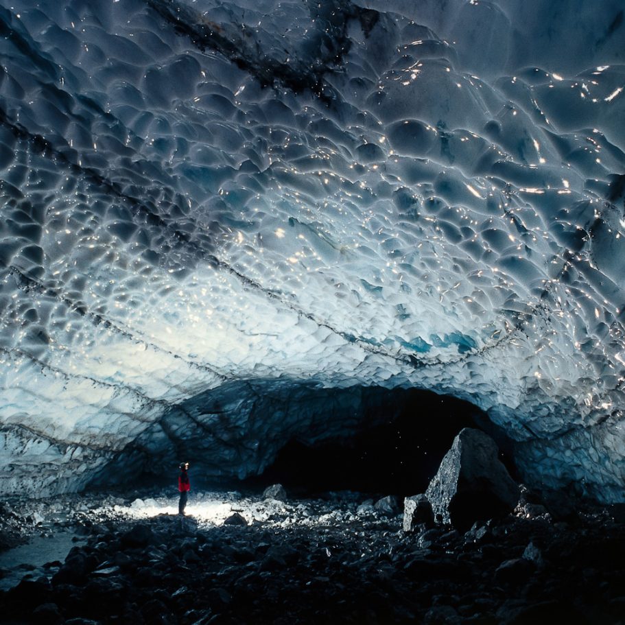 Caver in a large ice tunnel that has formed at the bottom of a glacier