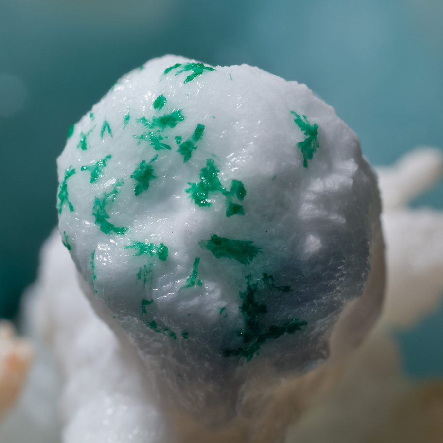Macro-photo of tiny, green crystals on a white aragonite helictite