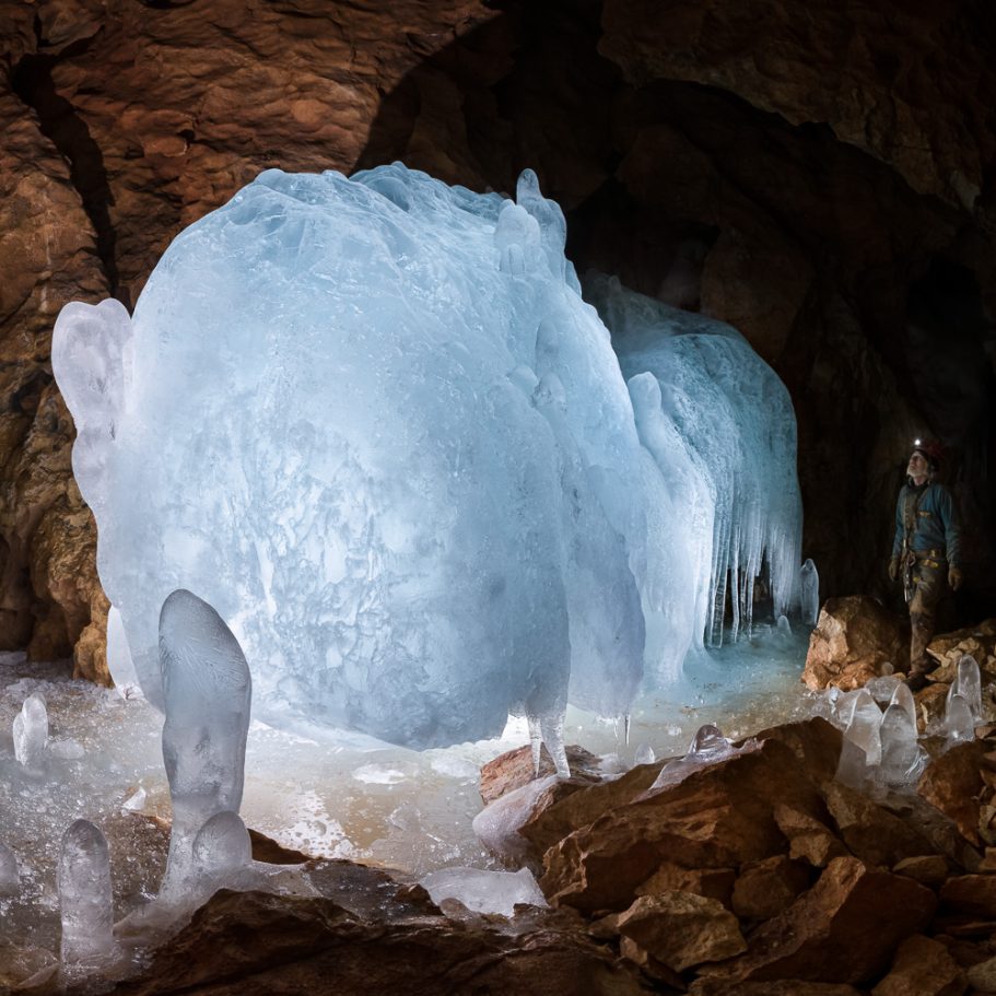 Blue ice formation in a large cave passage; caver for scale