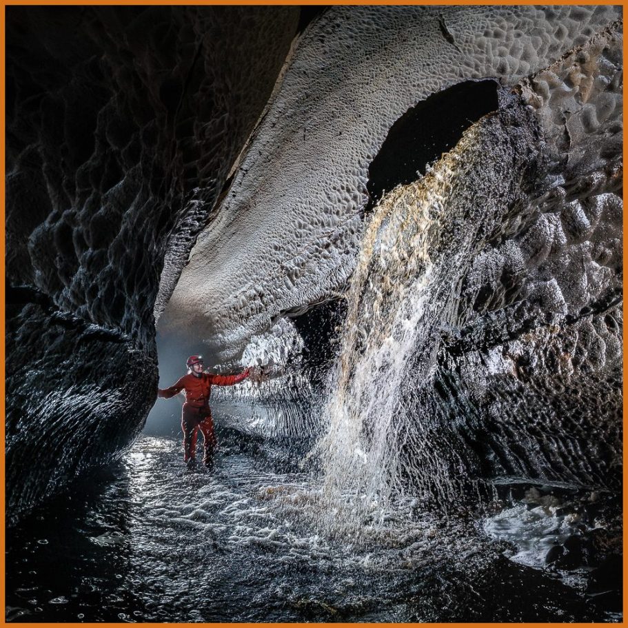 A caver admiring an underground water fall; title photo for "Voices of Water" portfolio