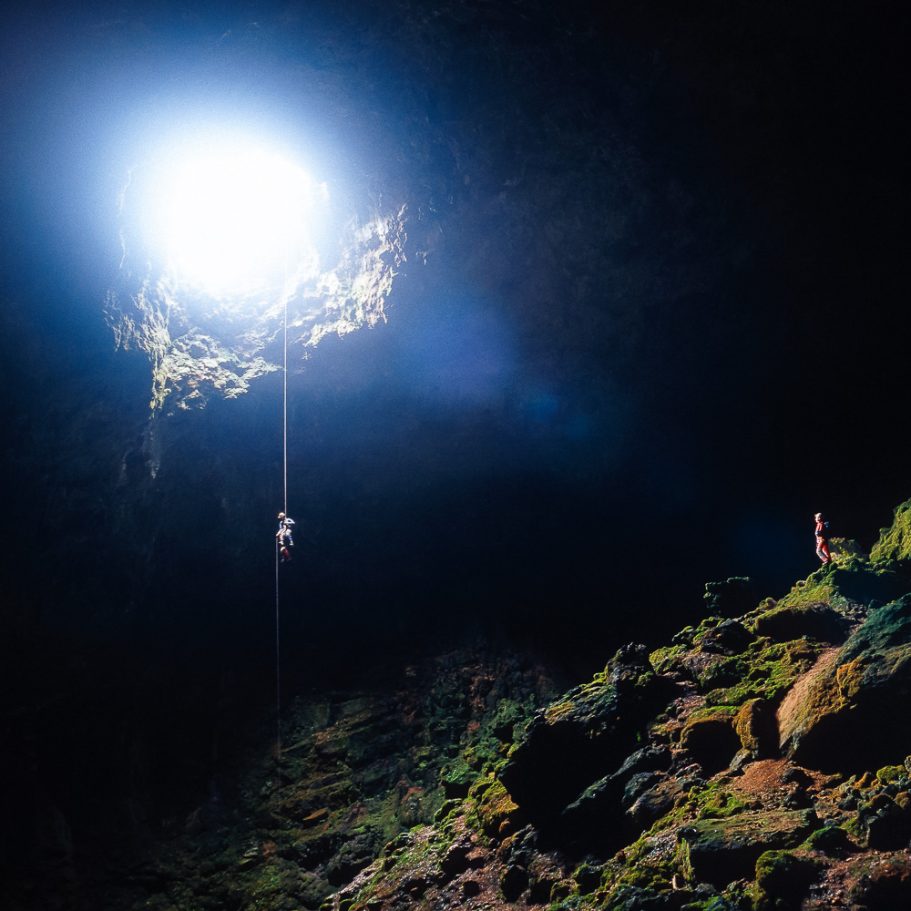 Caver rapelling into a large cave passage