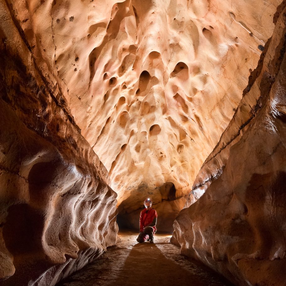 Caver in cave passage with scallops on the walls