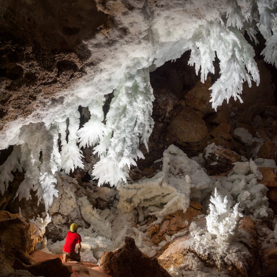 Caver looking at gypsum crystal aggregates in the 'Chandelier Ballroom' of Lechuguilla Cave