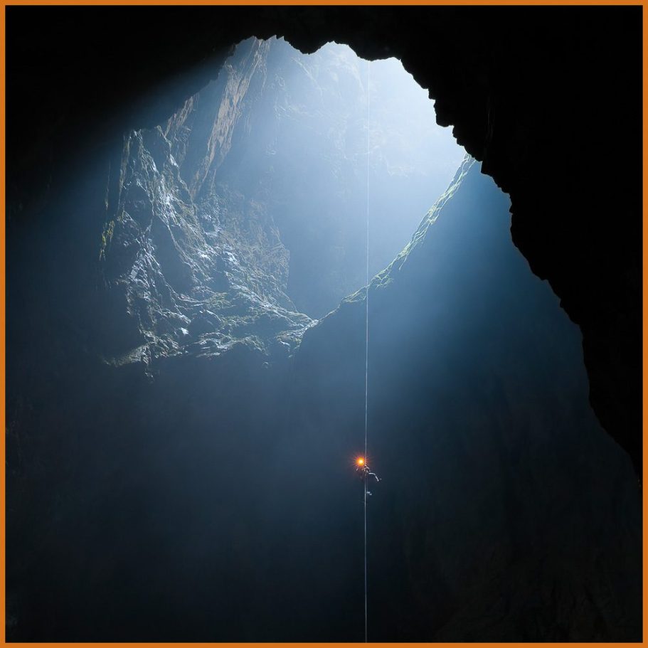 A caver abseiling into the twilight of a vast cave entrance pit; title photo for "Twilight Zone" portfolio