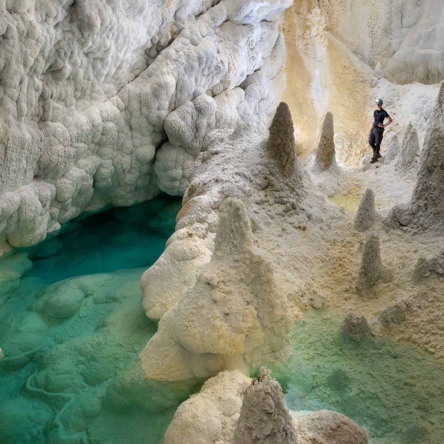 Caver surrounded by tall raft cones at a lake in 'Hudson Bay' in Lechuguilla Cave