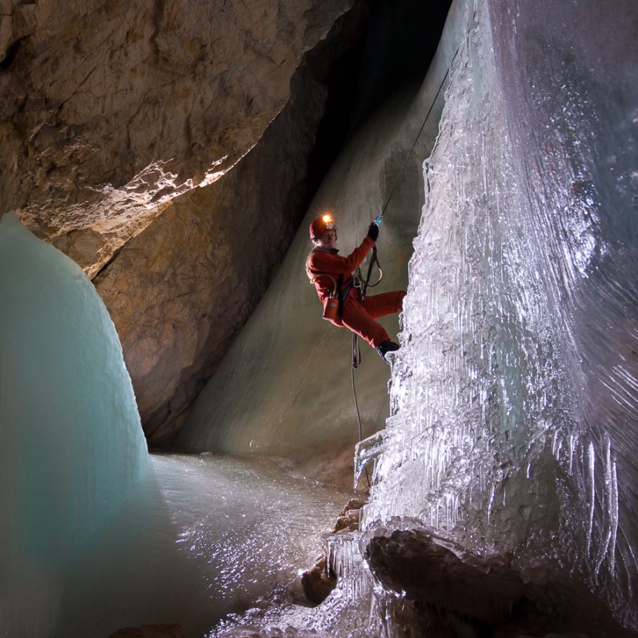 Caver rapelling an ice cascade in a cave
