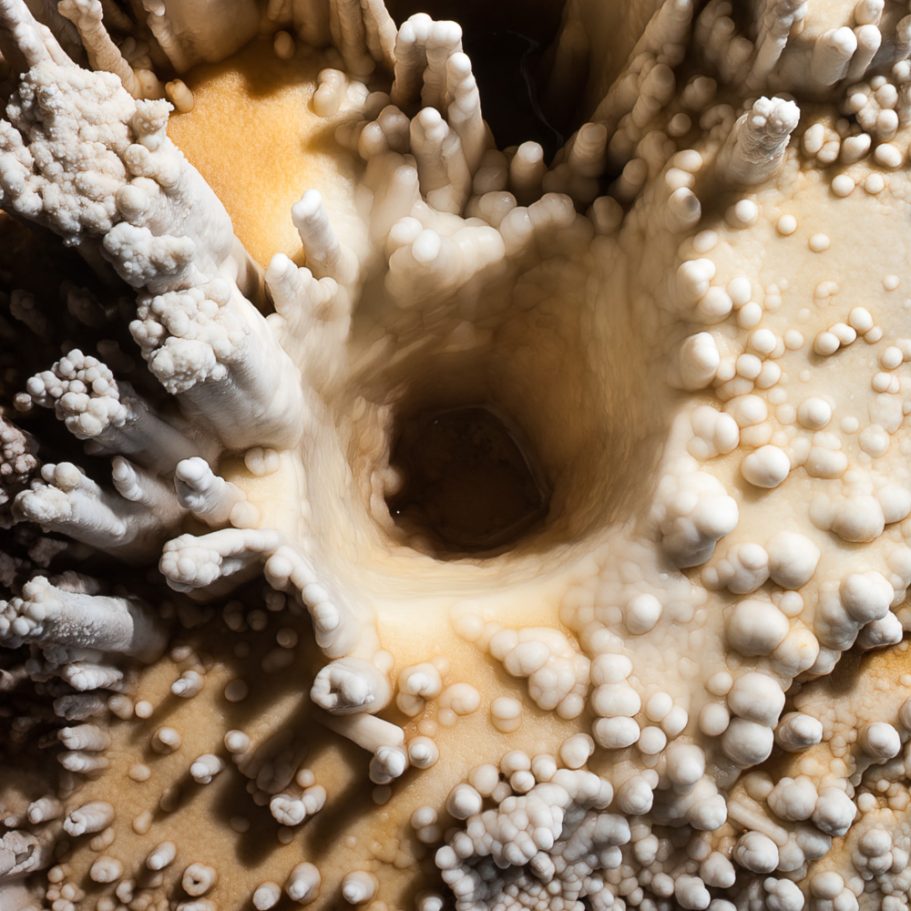 Calcite formations with a deep drip-hole in the floor of Lechuguilla Cave