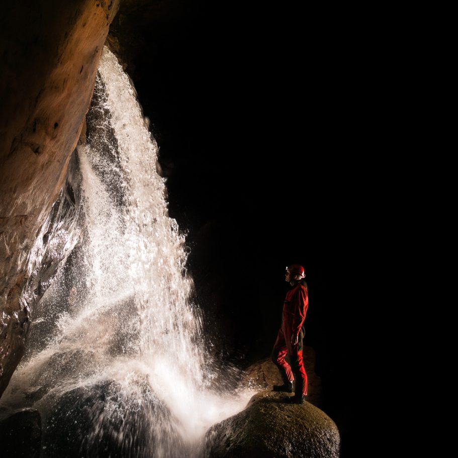 Large underground waterfall with caver for scale