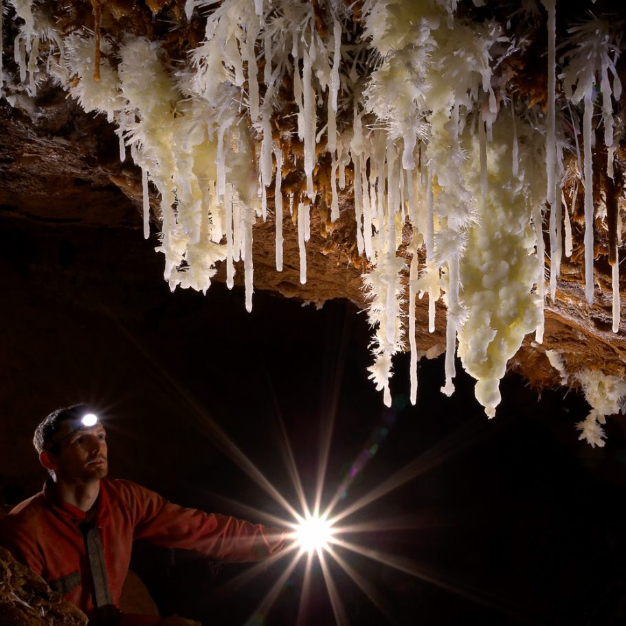 White aragonite cave formations with a caver providing backlight