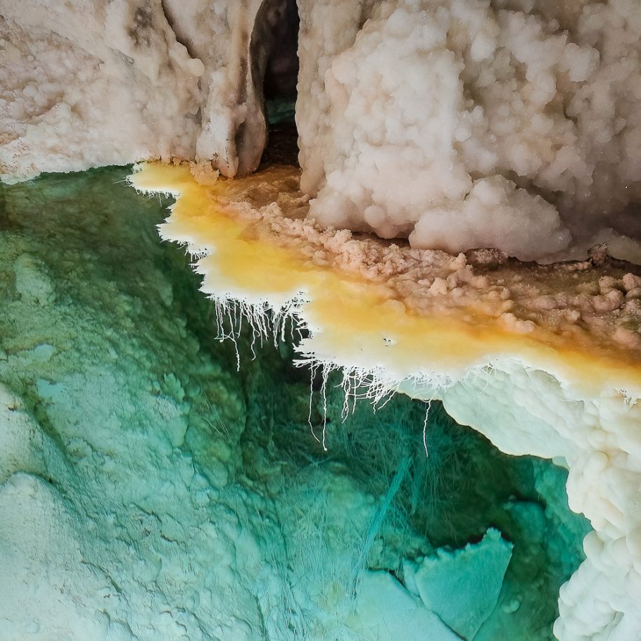Subaqueous helictites growing from a calcite rim in a bluish cave pool